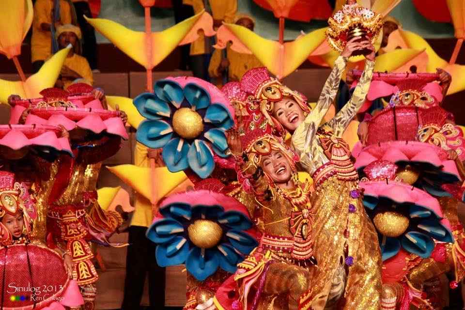 Sinulog dancers in gold costumes holding up a Santo Niño image