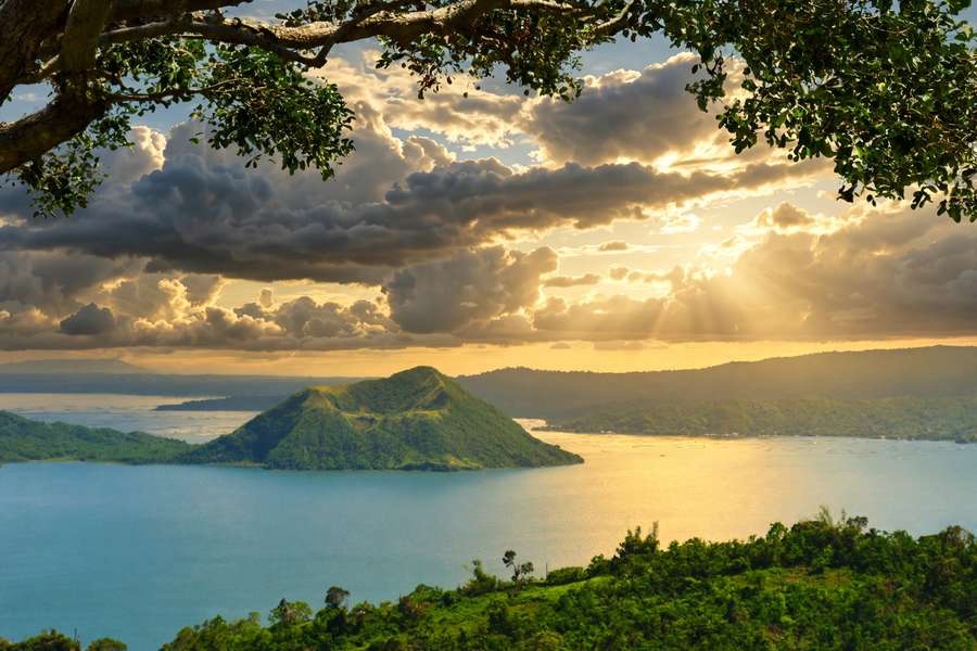 Taal Volcano island in Taal Lake seen from the Tagaytay ridge under golden late-afternoon clouds